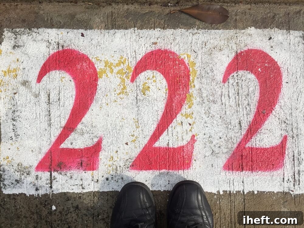 The number 222 in red paint on the ground over a white background with feet in black boots at the bottom of the image. 