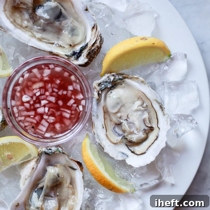 Raw oysters on the half shell on a plate of ice with a small bowl of mignonette sauce.
