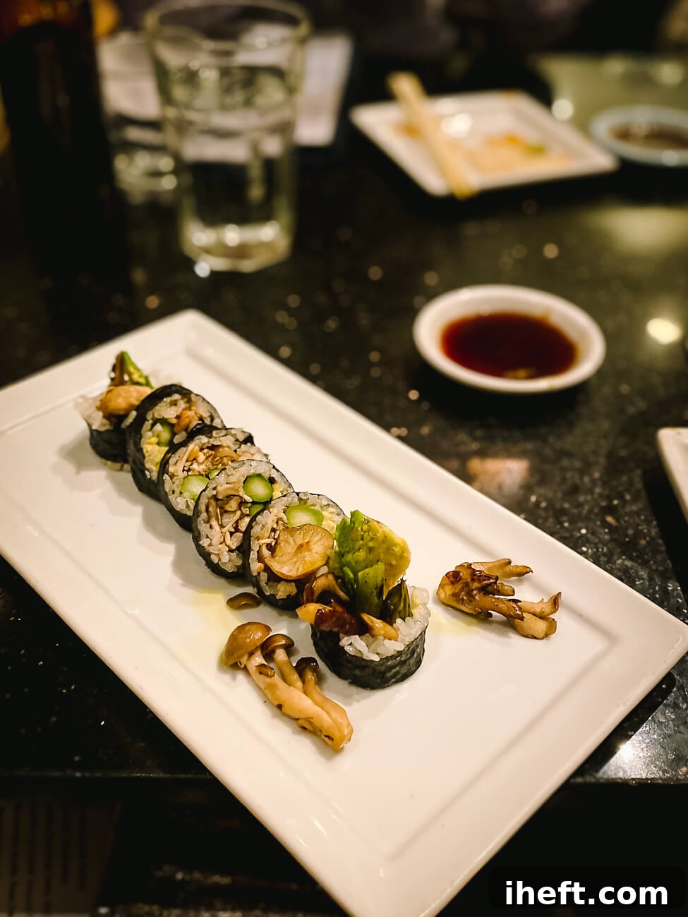 A pristine white plate showcases a gourmet vegan mushroom sushi roll, artfully prepared and presented within the elegant setting of a restaurant.