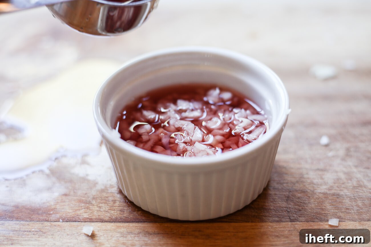 Red wine vinegar is poured over shallots to make mignonette sauce.