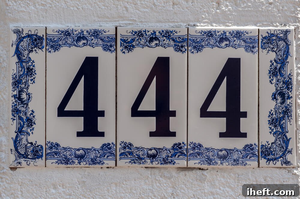White and blue ceramic address tiles on a white wall. The number 444 in black.