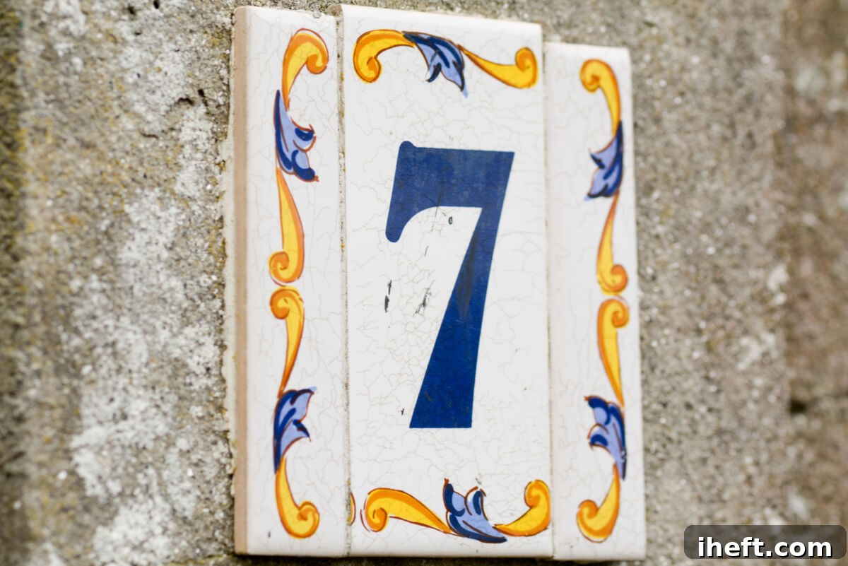 An address tile with a blue number 7 and yellow and blue decorative paint on a stone wall, symbolizing spiritual insight.