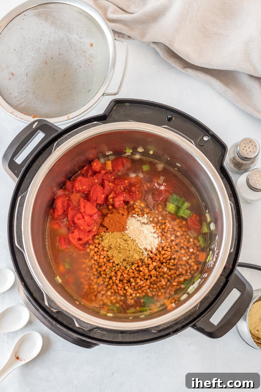 An Instant Pot is brimming with all the colorful ingredients necessary to create a delicious and wholesome vegan lentil chili, ready for cooking.