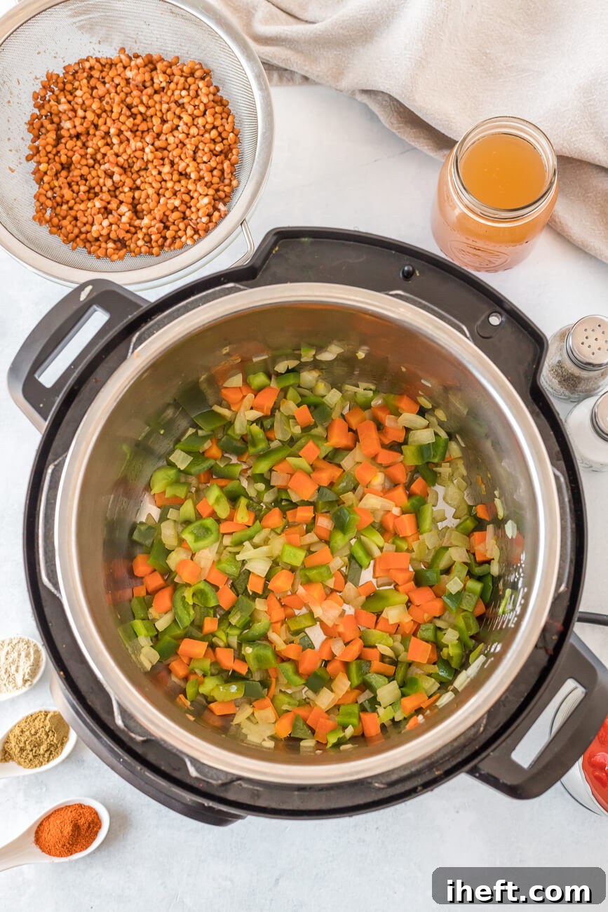 Diced onion, carrot, and bell pepper gently sautéing in the Instant Pot, forming the aromatic base for the chili.