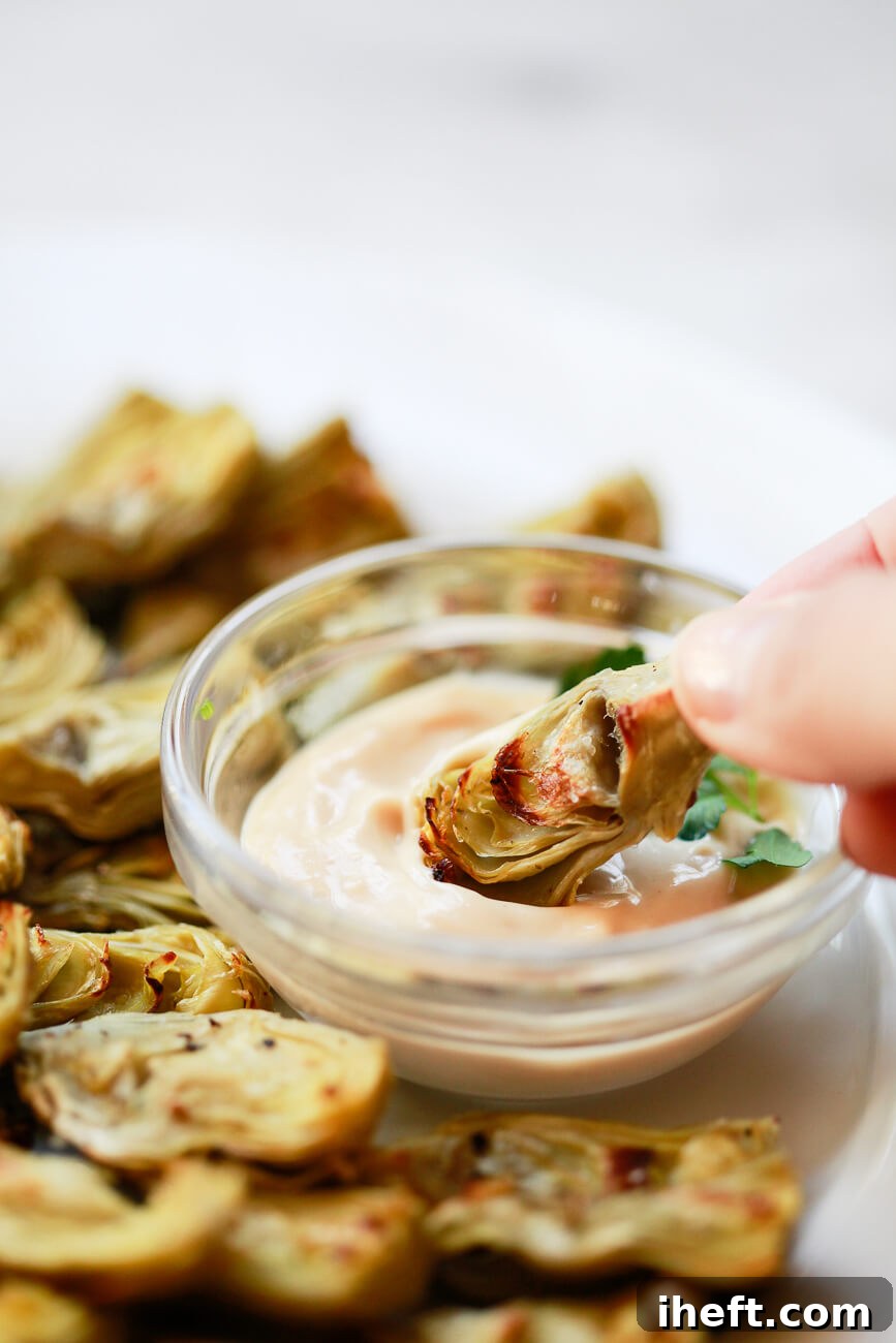 A crispy artichoke heart is dipped into aioli sauce.