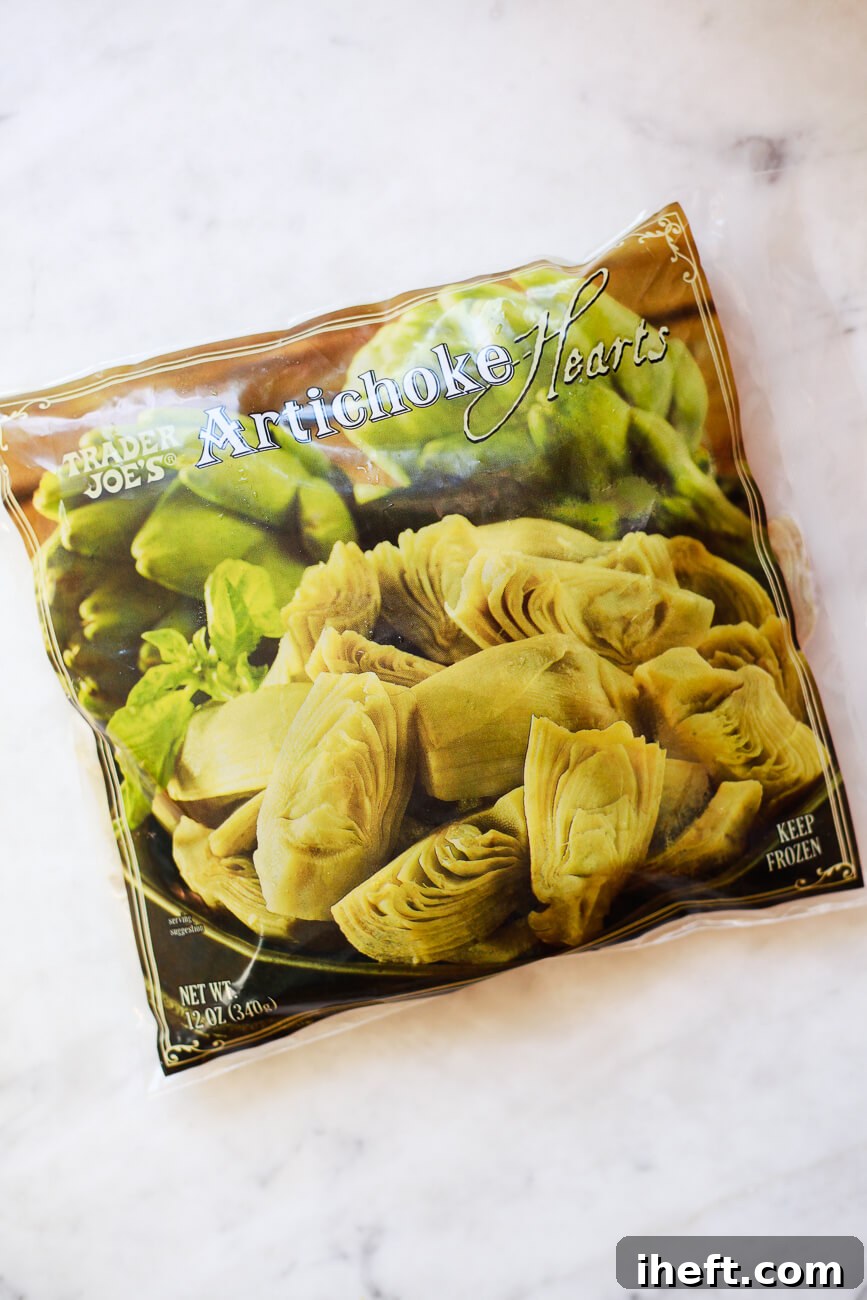 A bag of Trader Joe's Frozen Artichoke Hearts sits on a white marble countertop.