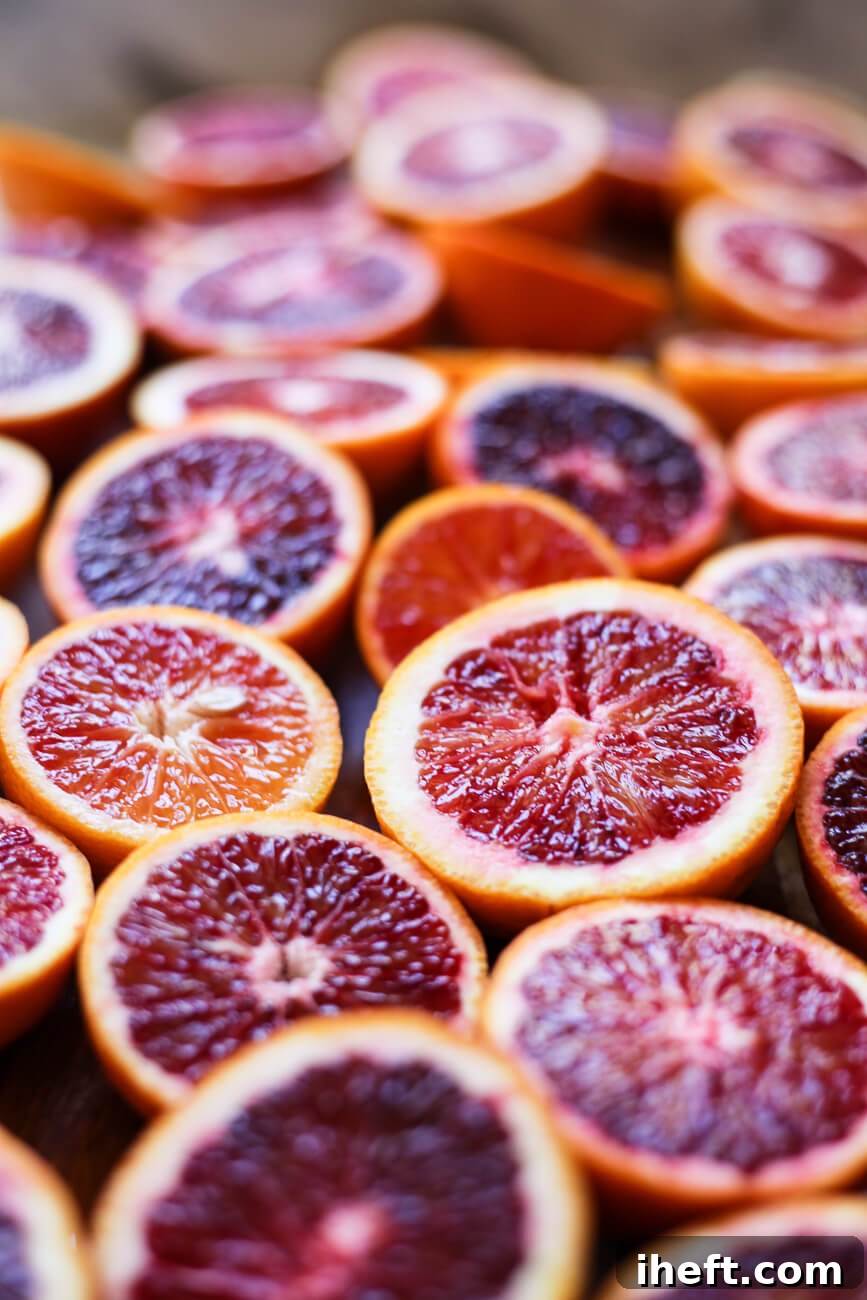 A close-up of red blood orange halves face-up on a cutting board.