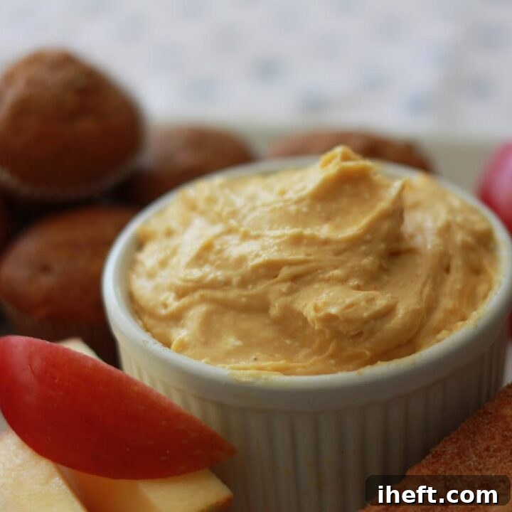 pumpkin cheesecake dip in a ramekin served with mini pumpkin muffins and apple slices.