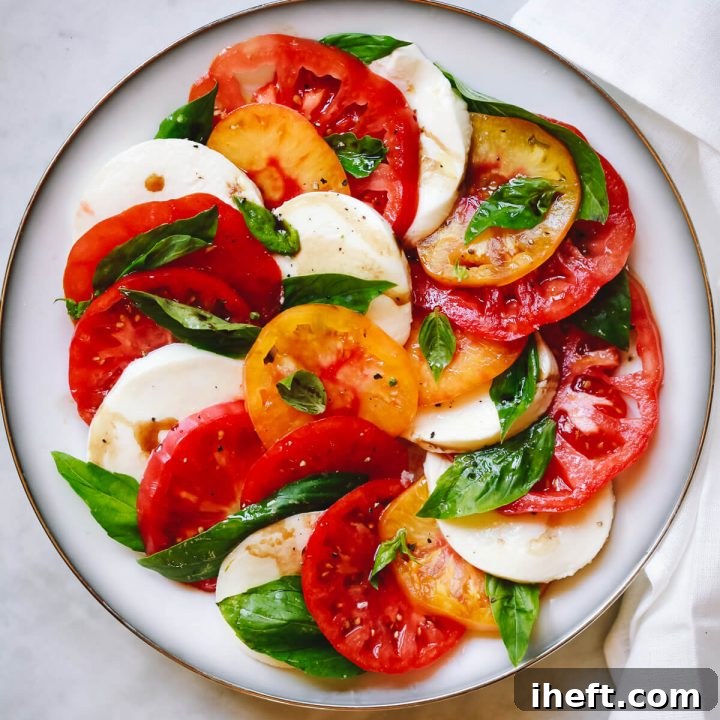 A beautiful plate of Caprese salad made with fresh tomatoes, creamy mozzarella, and fragrant basil leaves.