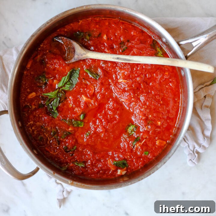 An overhead photo of San Marzano red sauce in a large saucepan on a white kitchen counter.
