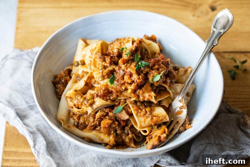 A white bowl filled with homemade pappardelle pasta and a vegan lentil ragu. 