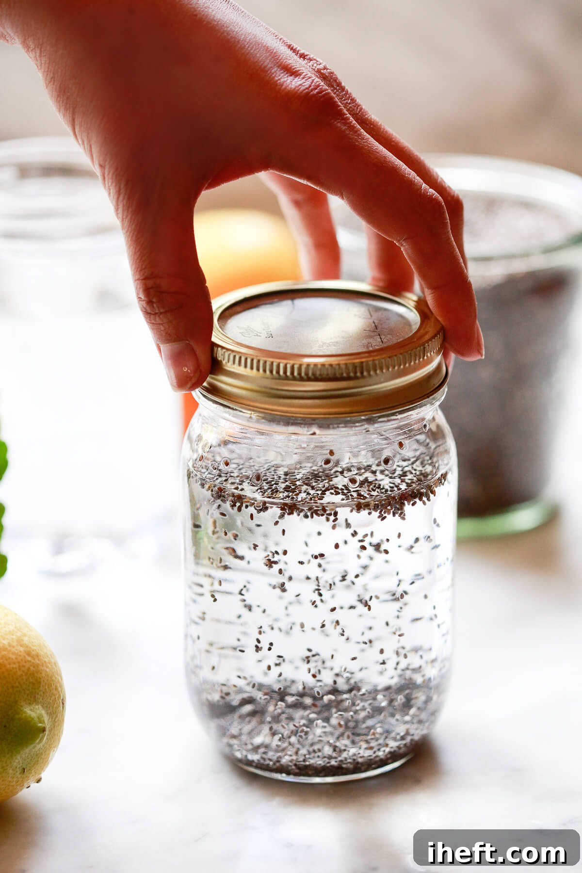 A mason jar filled with chia seeds in water is picked up to shake.