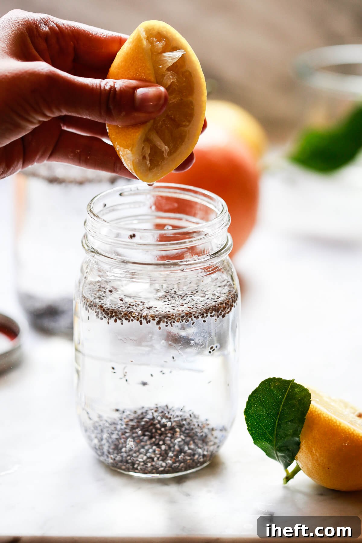 Half a lemon is squeezed over a jar of chia seeds in water drink.