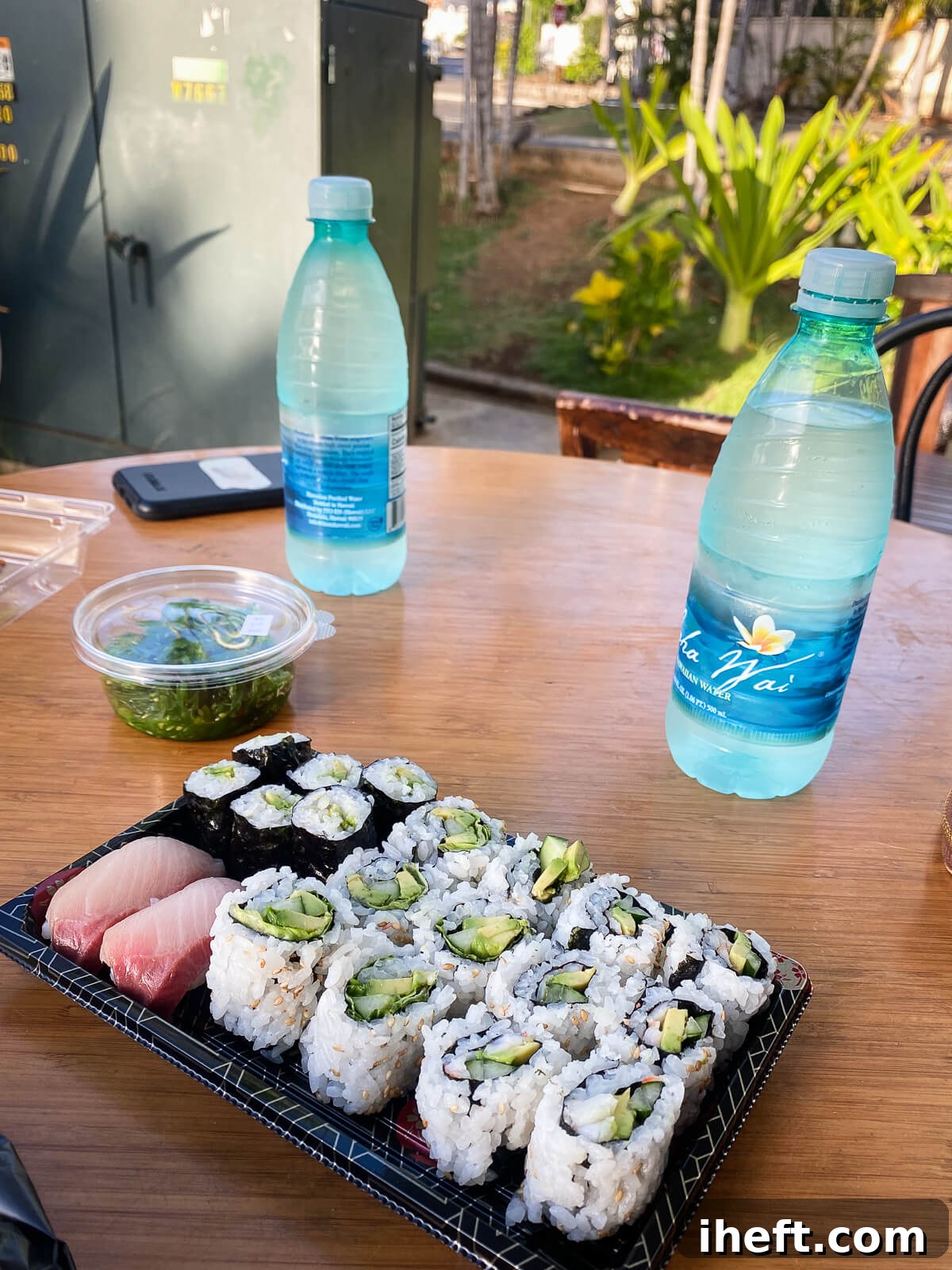 Assorted avocado, cucumber and hamachi sushi at Hawaii Sushi in Honolulu with a small dish of seaweed salad and two bottles of water. 