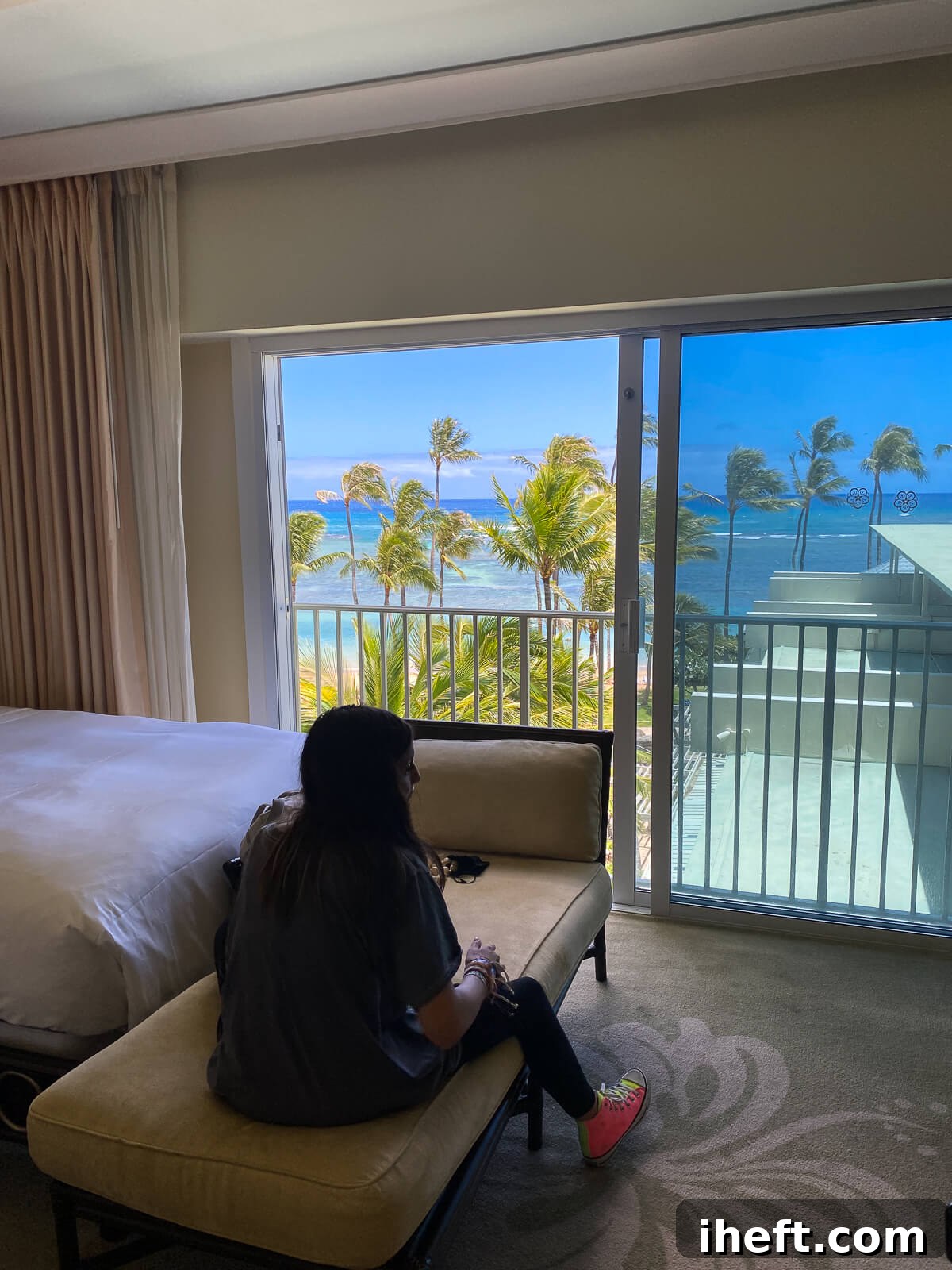 The inside of an Ocean View room at the Kahala Hotel on Oahu. A teenage girl sits on a lounge in the room. 