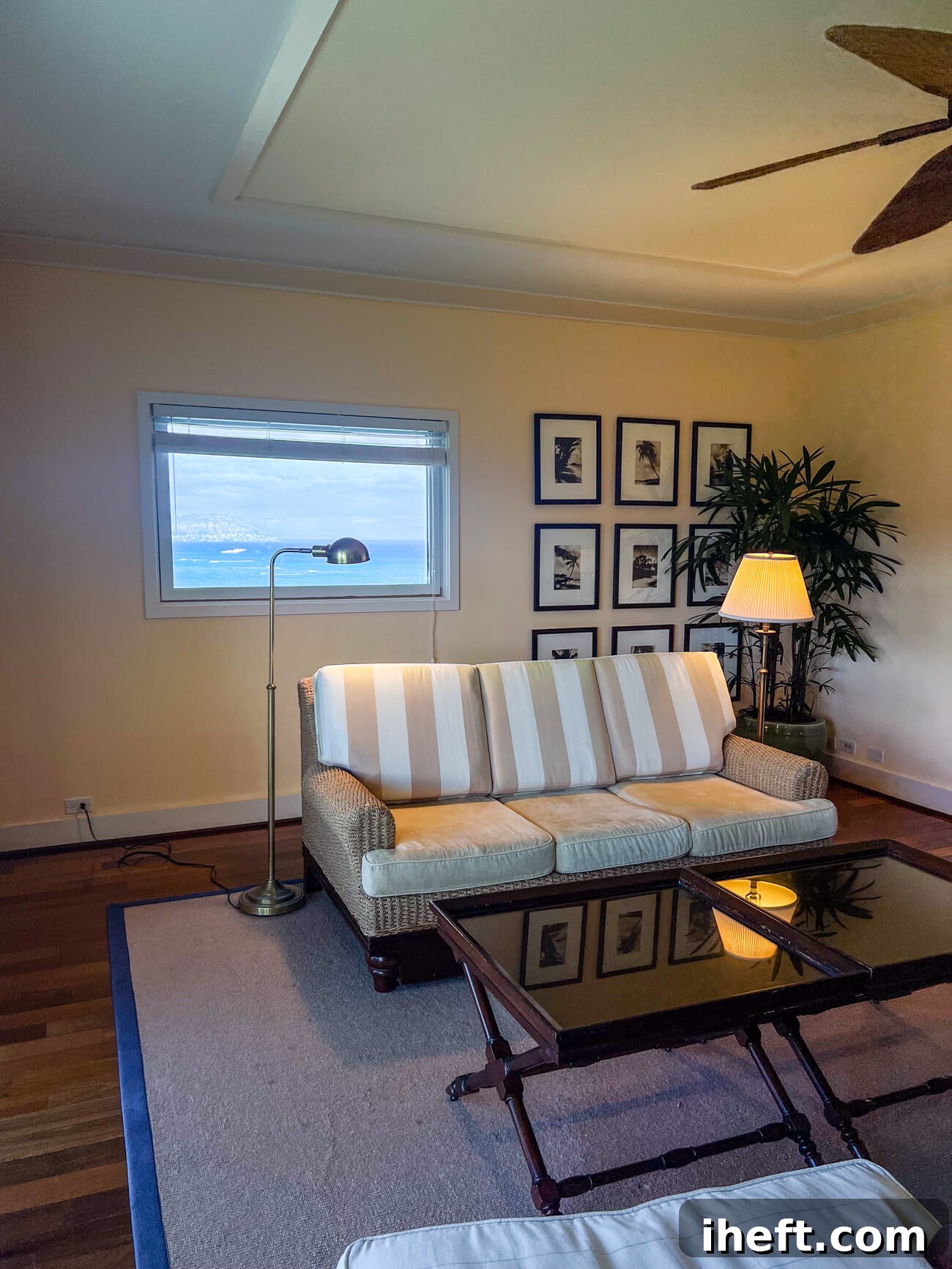 Living room of the Partial Ocean View Suite at the Kahala Resort Oahu with a striped sofa and beautiful ocean view from a rectangular window.