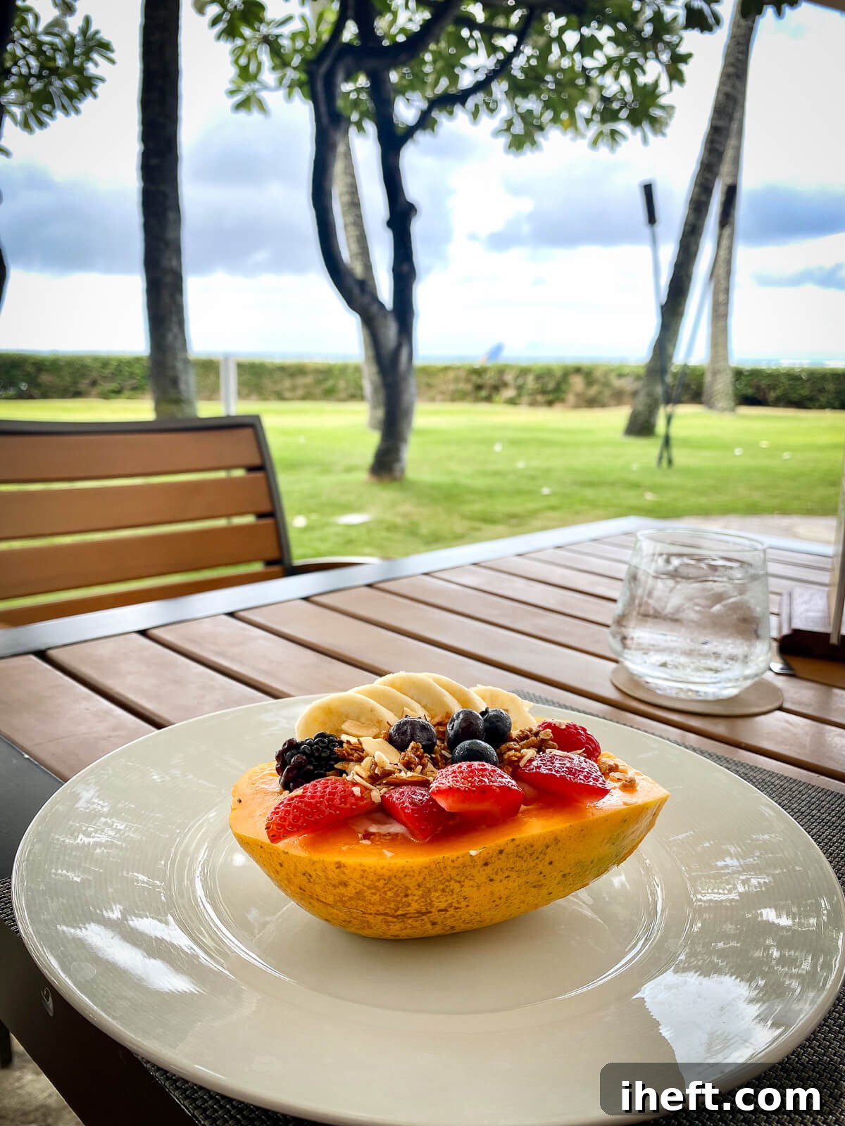 Half of a Hawaiian papaya filled with yogurt, granola and fruit on an outdoor table at Plumeria Beach House restaurant at the Kahala resort. 