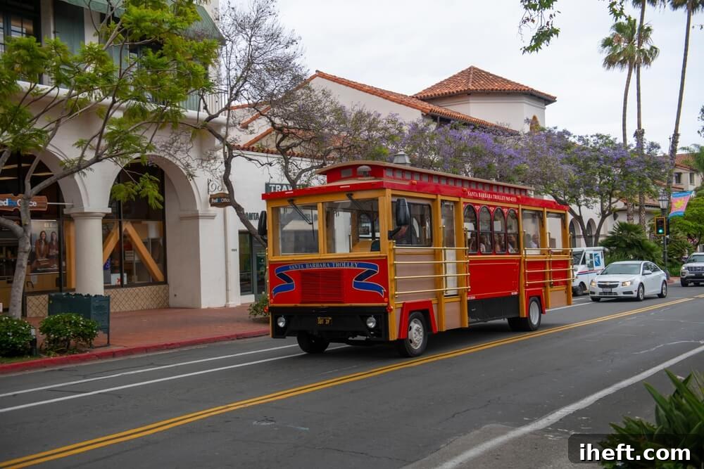 A red historic trolley drives up State Street in Santa Barbara. 