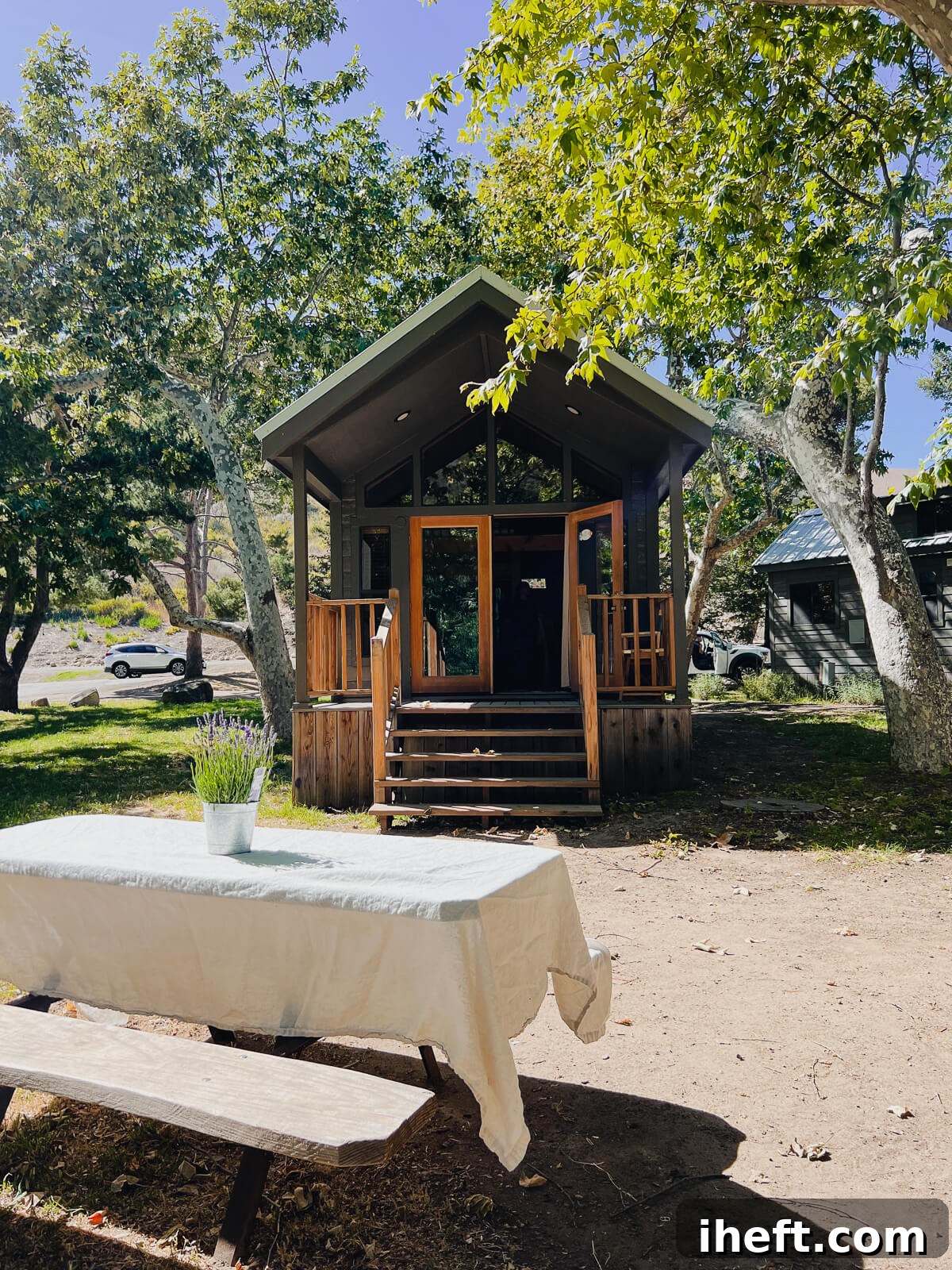 A beautiful cabin at the El Capitan Canyon resort with a linen tablecloth covered picnic table in front. 
