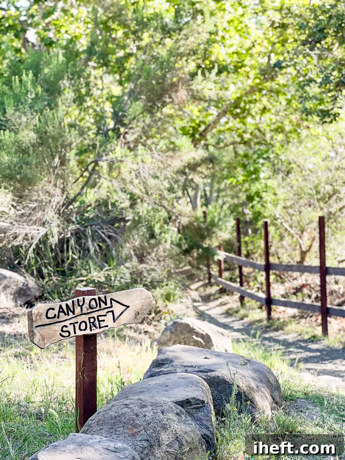 A scenic trail leading through the El Capitan Canyon, marked by a rustic wooden sign pointing the way to the "canyon store" with an arrow, inviting exploration and discovery.