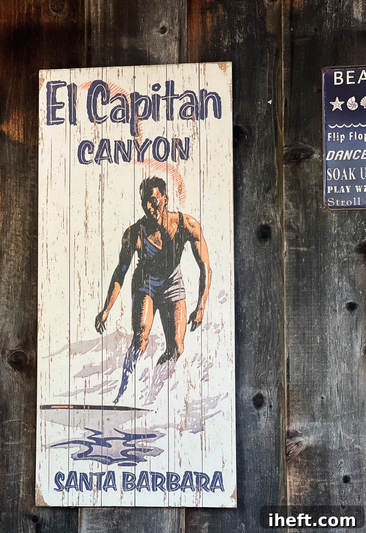 A charming, vintage-inspired wooden sign featuring a painting of a surfer gracefully riding a wave, with the inviting text "El Capitan Canyon Santa Barbara," welcoming visitors to this coastal paradise.