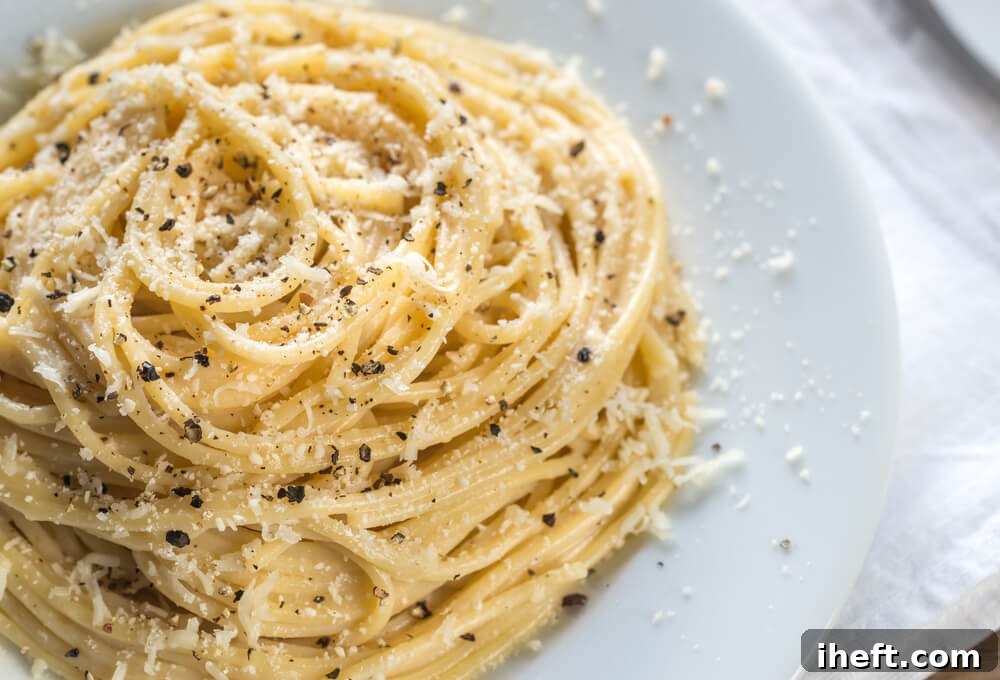 A close-up of a bowl of Cacio e Pepe, showcasing perfectly coated spaghetti with a creamy, emulsified cheese and black pepper sauce.