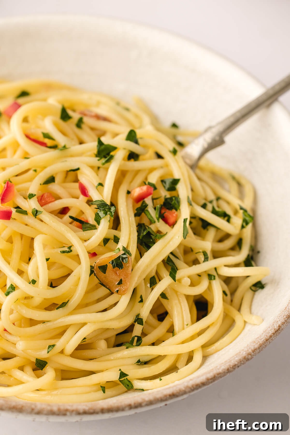 A simple ceramic bowl of spaghetti aglio e olio, glistening with olive oil and garlic, a testament to minimalist Italian cooking.