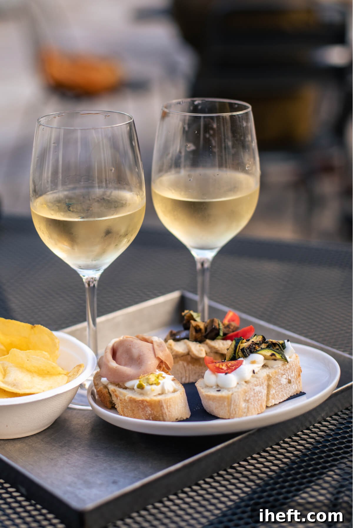 Three colorful Cichetti on a rustic table in Venice, Italy, accompanied by two glasses of white wine, capturing the essence of a Venetian aperitivo.