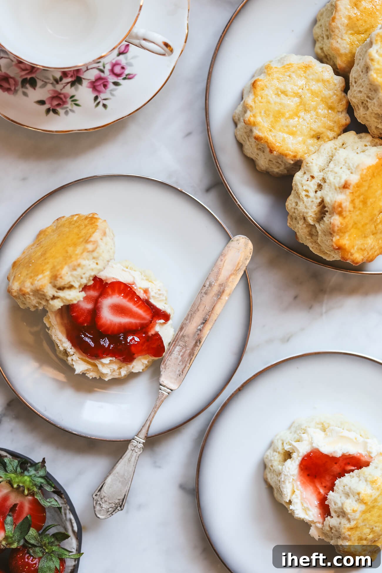 Exquisite English scones, beautifully arranged with a generous dollop of clotted cream and a spoonful of vibrant strawberry jam.