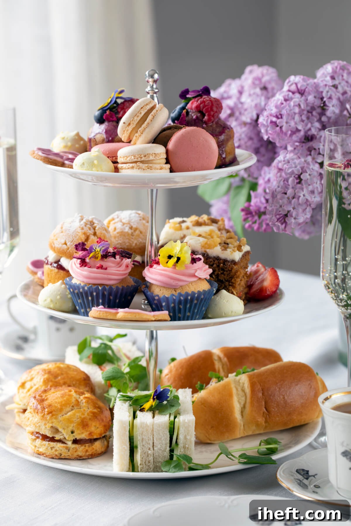 An elegant spread for afternoon tea, featuring a tiered stand laden with savory sandwiches and sweet treats, accompanied by a pot of tea and delicate cups.