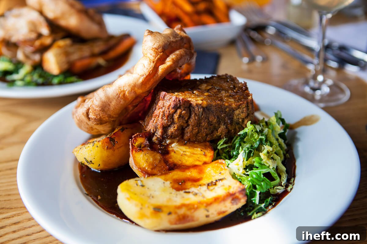 A plate showcasing a plant-based meat roast, alongside perfectly roasted potatoes, a fluffy Yorkshire pudding, and vibrant green vegetables, exemplifying a traditional British Sunday Roast.