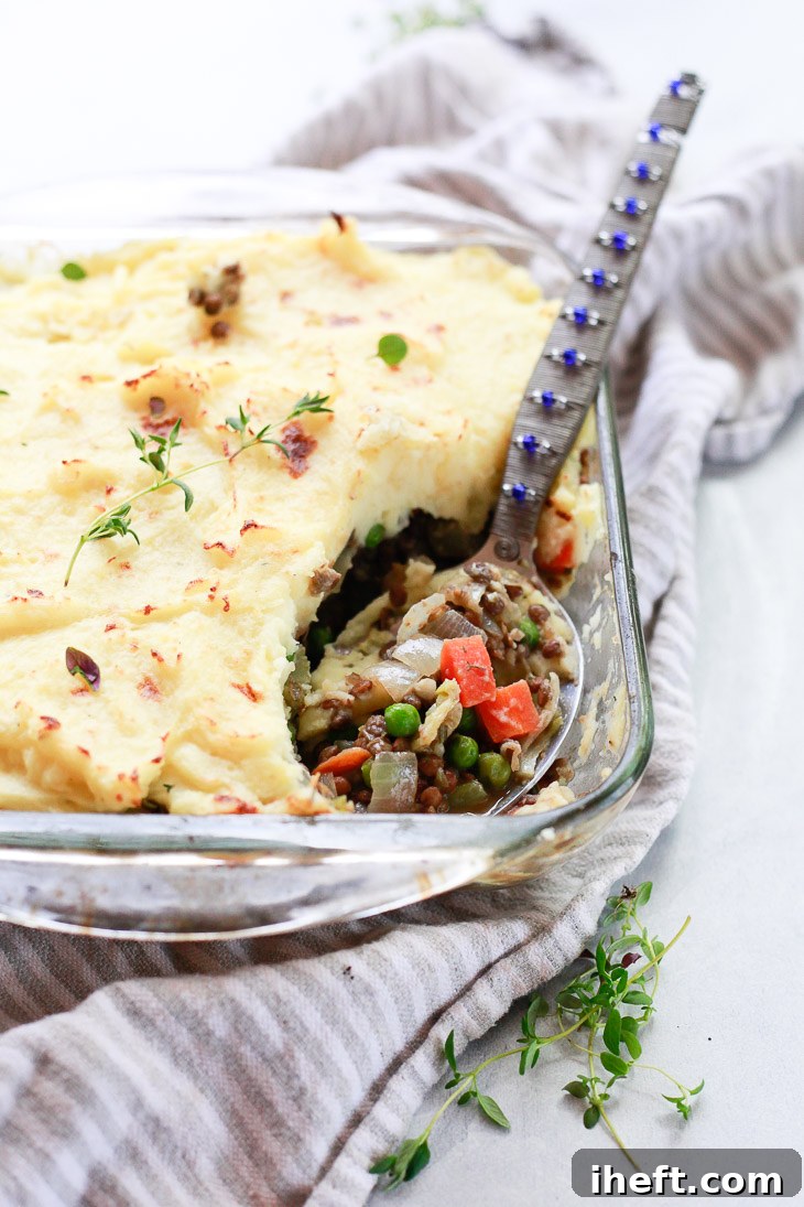 A comforting casserole dish filled with lentil shepherd's pie, showcasing peas, lentils, and carrots beneath a creamy mashed potato topping.