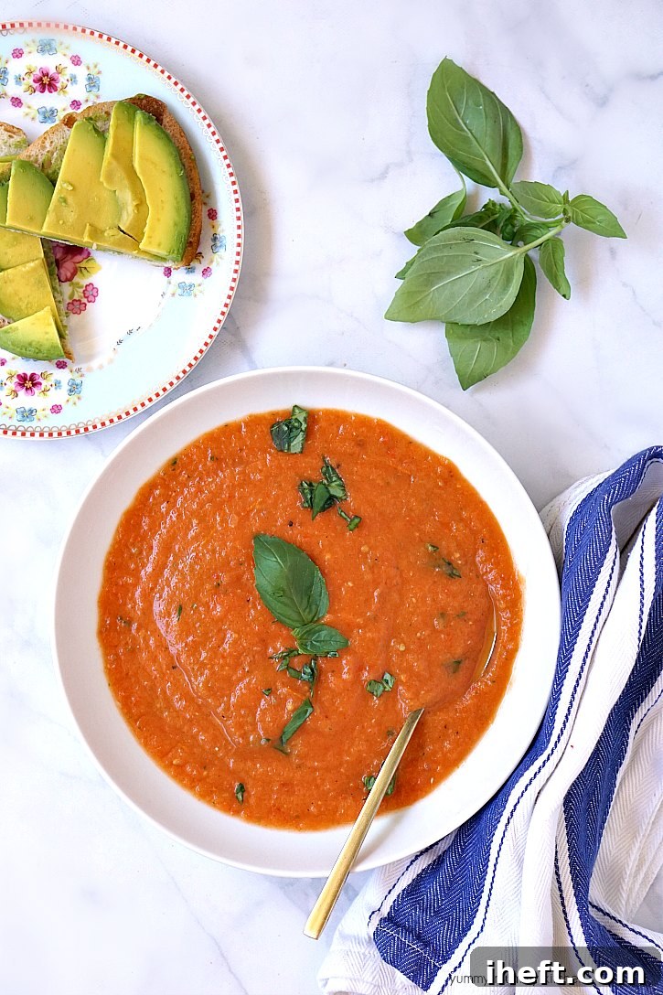 A vibrant bowl of fresh tomato soup, made from roasted tomatoes and basil, perfect as a light vegan summer meal.
