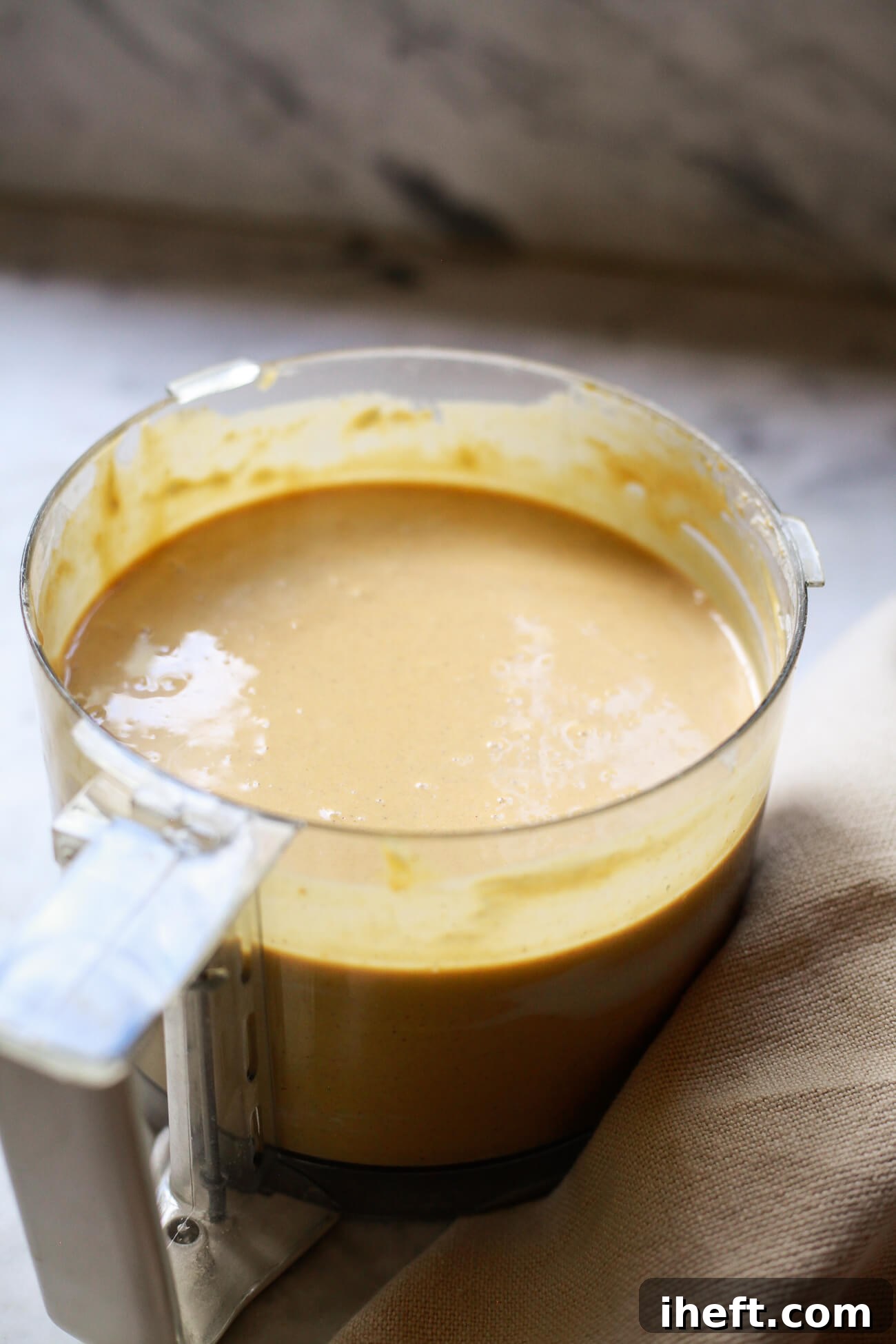 The luxurious pumpkin pie cheesecake batter swirling in a food processor, perfectly smooth and ready for baking.