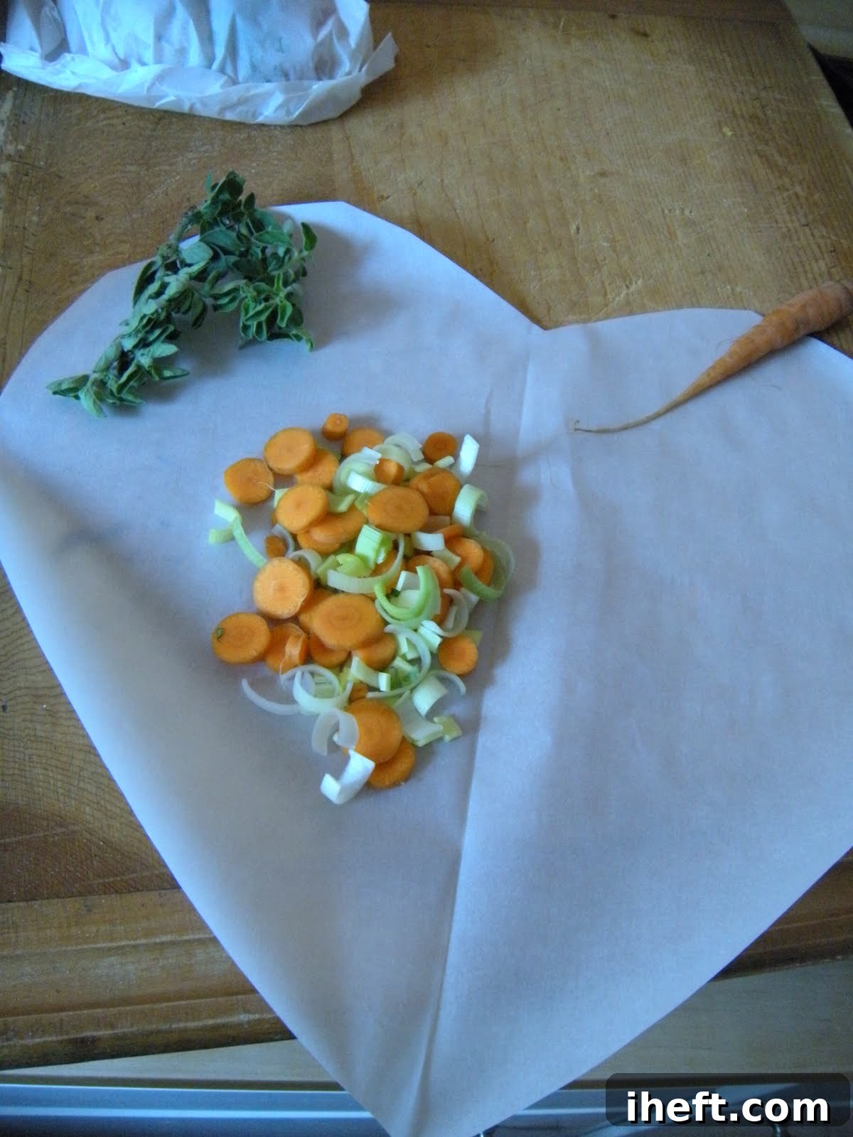 Close-up of a parchment paper packet, partially opened, revealing steam escaping and the cooked halibut and vegetables inside. 