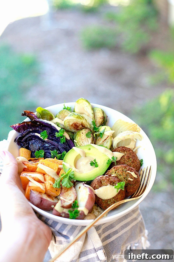 Falafel as part of a Buddha bowl filled with quinoa, vegetables, avocado, and tahini sauce. 