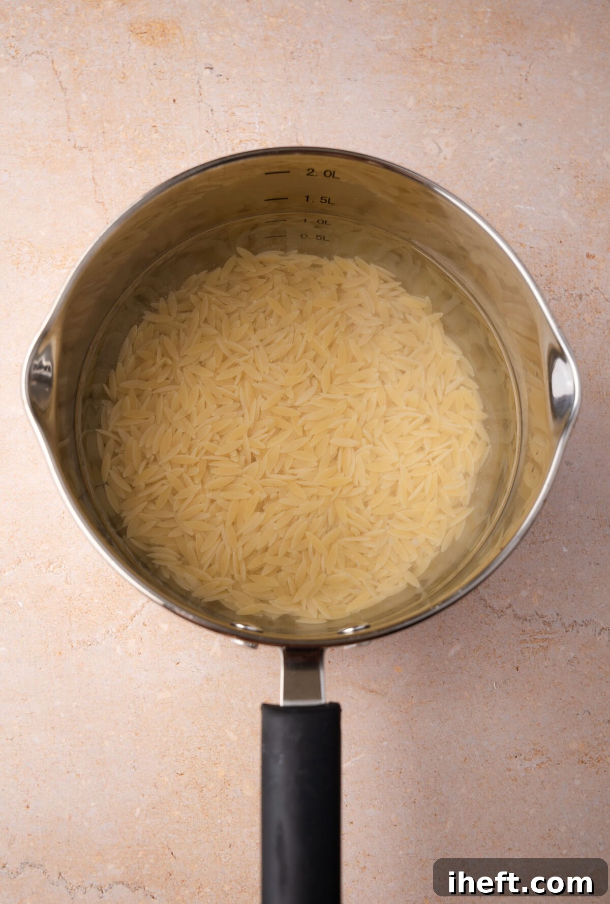 A small saucepan filled with water and orzo pasta.