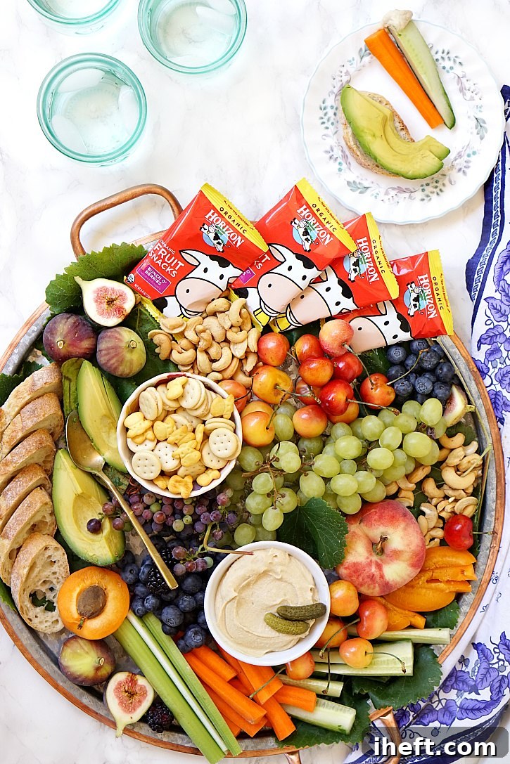 A big kid-friendly snack platter filled with fruit, veggies, hummus, crackers, nuts, and Horizon fruit snacks is perfect for any family party.