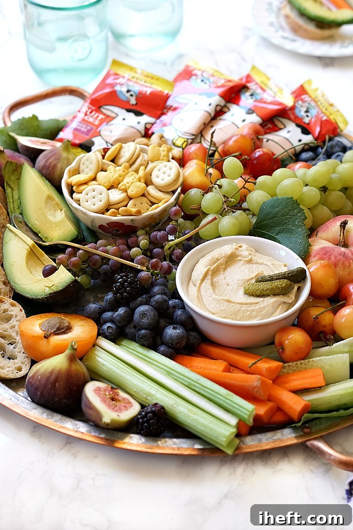 How to make a beautiful kid friendly party platter the whole family will love. Perfect for happy hour or birthday parties, this snack board is loaded with wholesome ingredients like fruit, veggies, nuts, hummus, and kids' snacks.