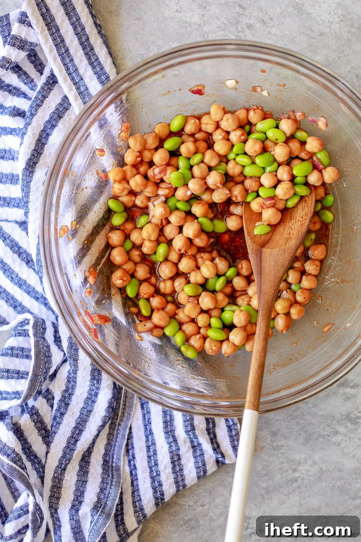 A bowl filled with chickpeas and edamame, thoroughly coated in the rich Korean BBQ marinade, ready for roasting.