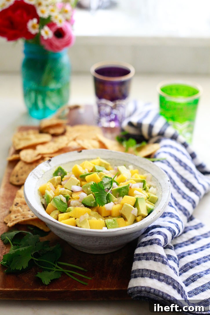 A vibrant bowl of fresh mango avocado salsa, brimming with colorful diced mango, creamy avocado, and aromatic herbs, served with a side of crispy tortilla chips, inviting you to dig in.