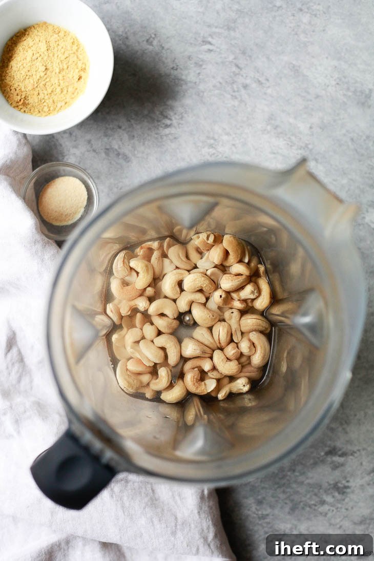 Soaked cashews in a Vitamix blender ready to blend with water, nutritional yeast, and garlic powder for a cashew cream sauce for vegan spinach artichoke dip. 