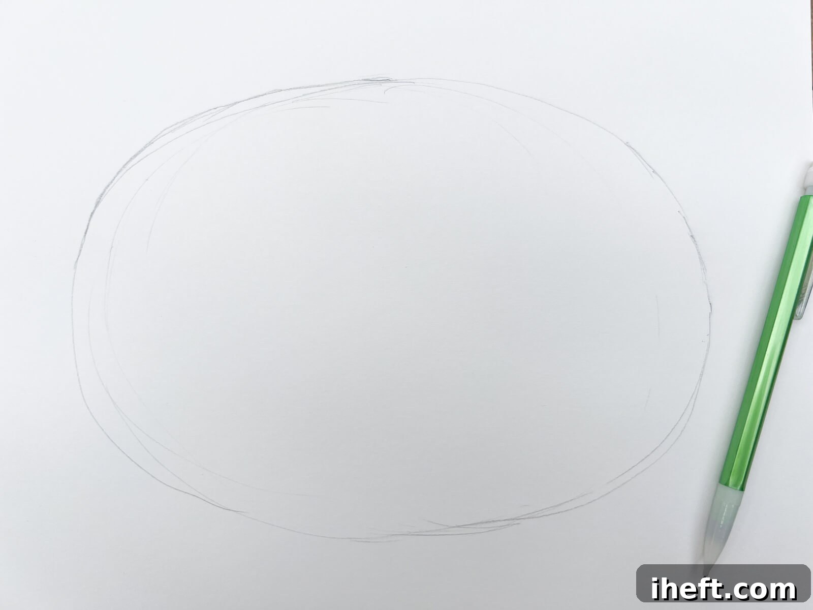 An oval is drawn on a white piece of paper in pencil to start an easy pumpkin drawing.