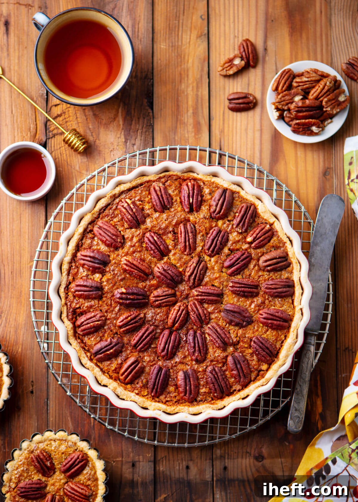 An overhead photo of a beautifully golden-brown homemade pecan pie in a rustic ceramic tart pan, perfectly set on a wire rack for cooling. This image illustrates the crucial initial step in storing pecan pie.