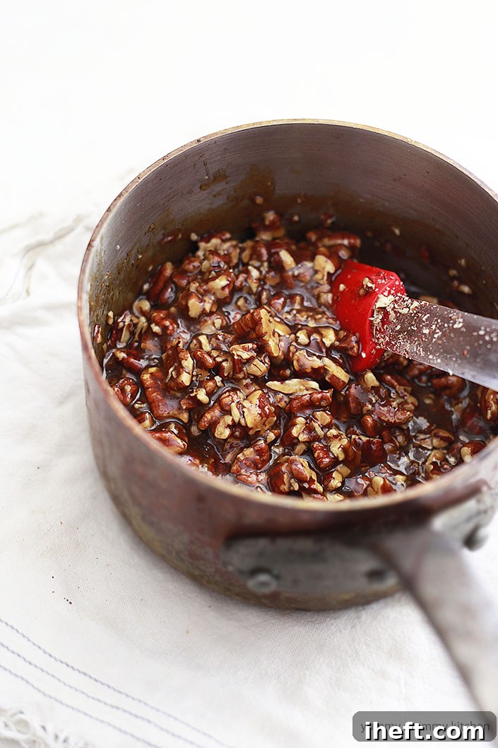 A small copper saucepan is used to prepare a rich, amber pecan pie filling, showing the liquid stage before baking.