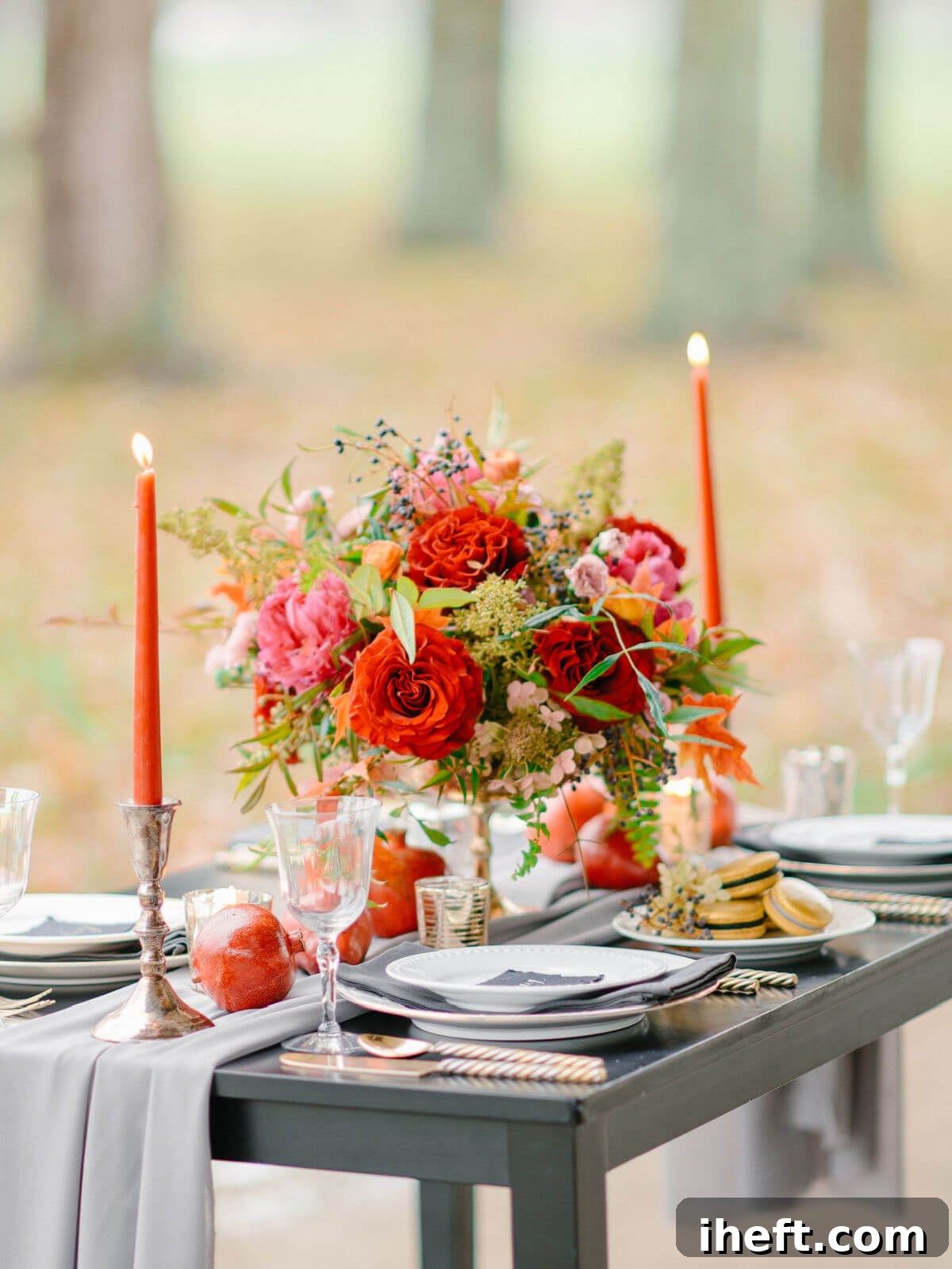 A luxurious and vibrant autumn table setting, showcasing a striking centerpiece of bright orange flowers and tall orange candles, elegantly complemented by a cool grey runner, for a bold and modern Thanksgiving.