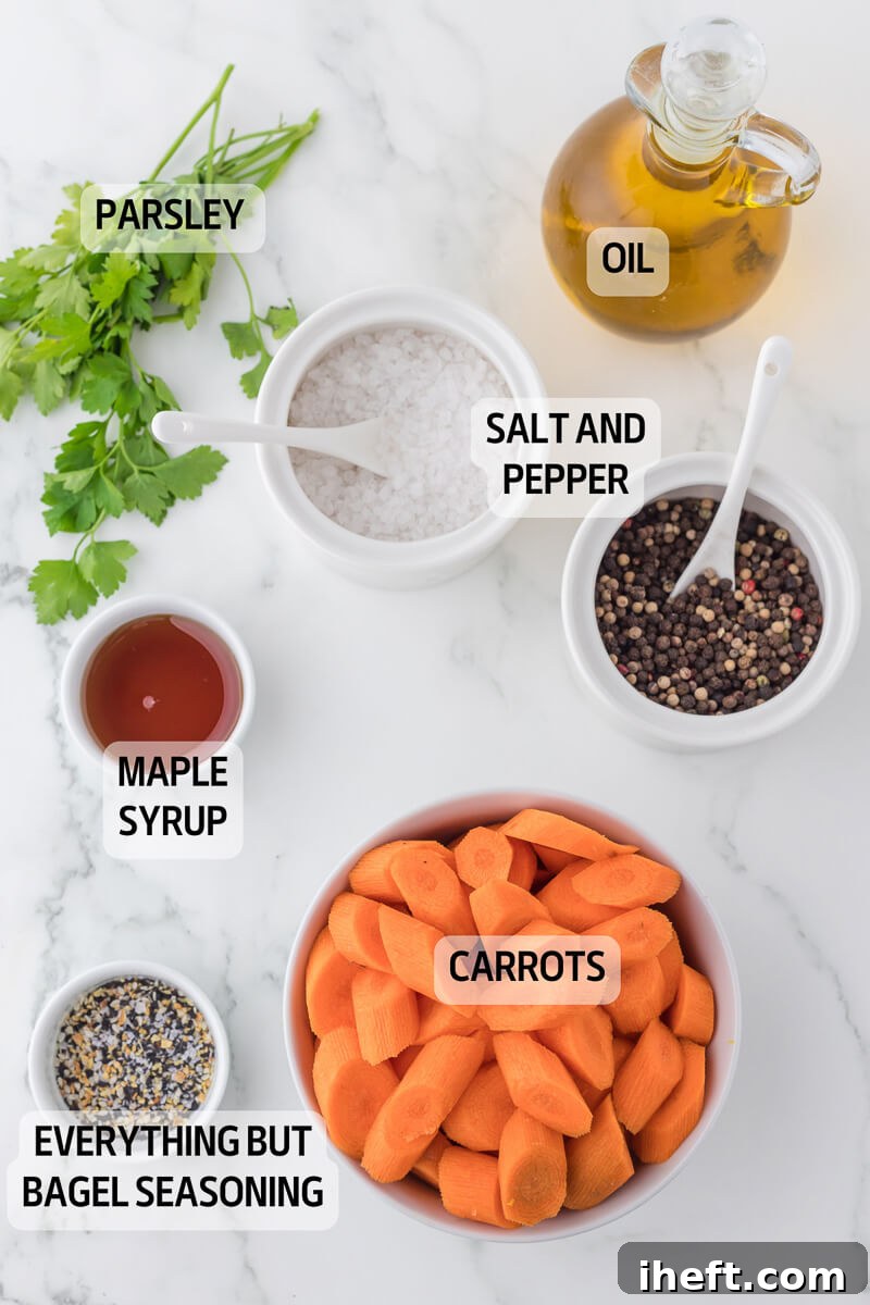 Various ingredients for air fryer carrots laid out in small bowls on a marble countertop, including olive oil, maple syrup, salt, pepper, and Everything Bagel Seasoning.