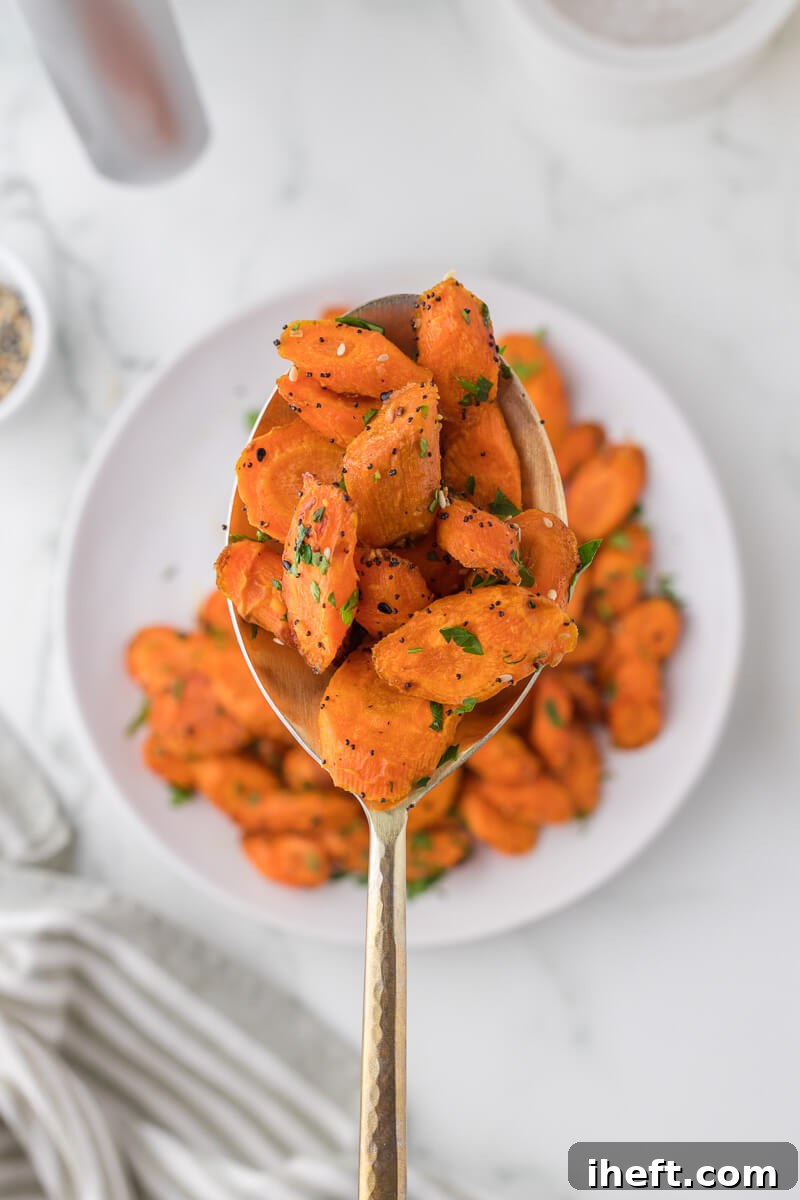 Close-up of golden-brown glazed carrot slices resting on a small gold serving spoon.