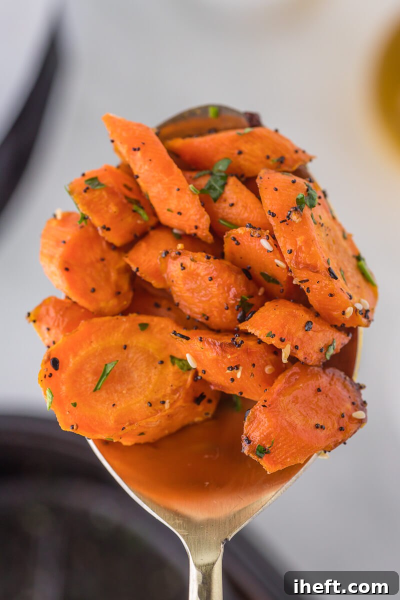 A close-up view of beautifully glazed and roasted air fryer carrot slices arranged on a golden serving spoon.