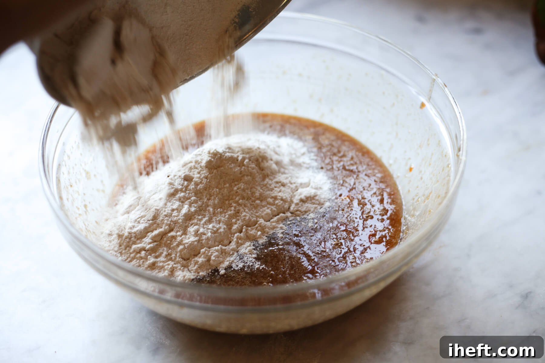The dry ingredients are carefully added to the wet ingredients in a large bowl, poised for gentle mixing to form persimmon bread batter.